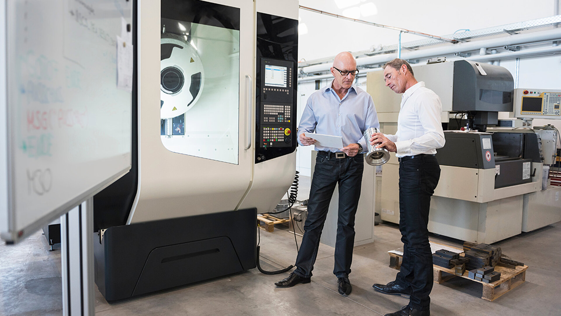 Zwei Mitarbeiter eines Industriebetriebes begutachten ein geliefertes Produkt und befinden sich an einem kritischen Punkt ihrer Customer Journey.