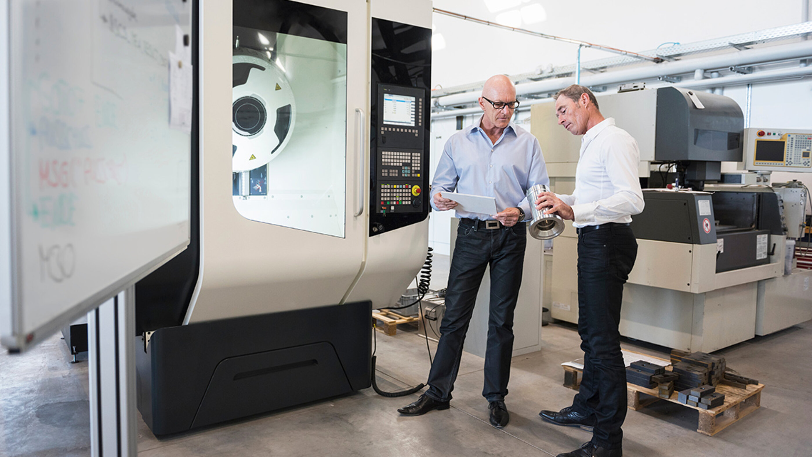 Jeder Touchpoint mit der Marke sollte für Kunden bewusst und positiv gestaltet werden. Zwei Mitarbeiter eines Industriebetriebes begutachten ein geliefertes Produkt und befinden sich an einem kritischen Punkt ihrer Customer Journey.