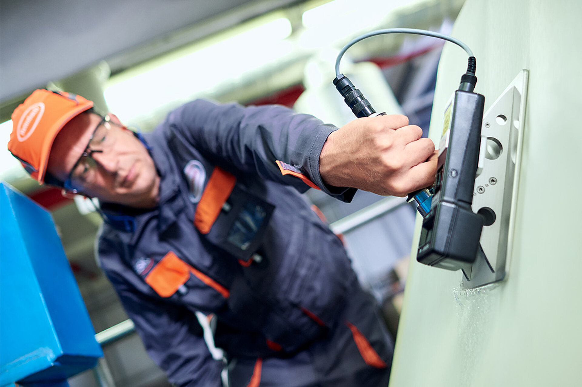 Ein Service-Techniker nimmt am Filz einer laufenden Papiermaschine eine Spannungsmessung vor. Eine geringe Spannung führt zum Durchhängen, eine hohe zum Dehnen der Papiers. Ein Abriss der Bahn kann die Folge sein. Ein Mitarbeiter des technischen Services nimmt am Filz einer laufenden Papiermaschine eine Spannungsmessung vor.