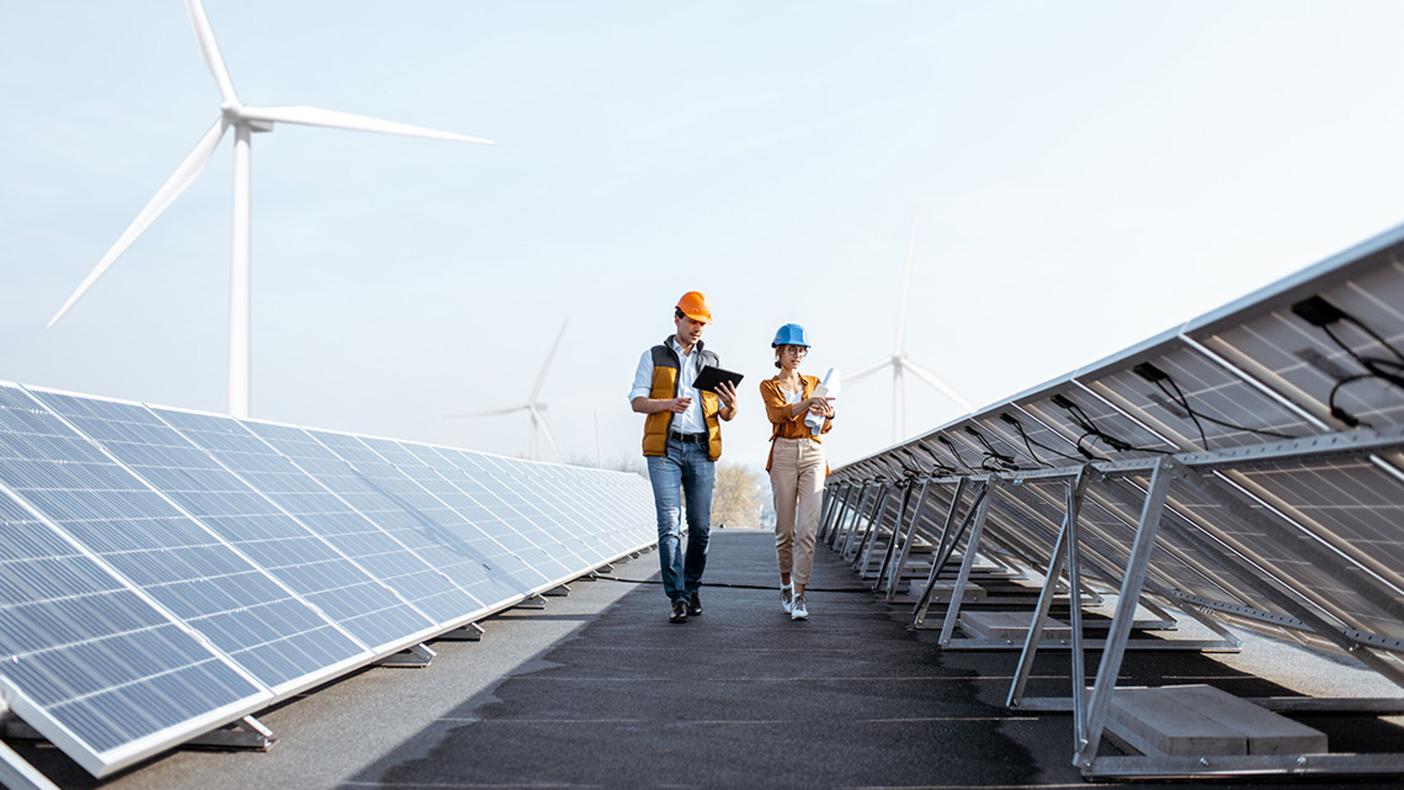 Die Stromproduktion aus Sonne und Wind schwankt je nach Wetter und Tageszeit, Produktion und Verbrauch liegen zudem zeitlich auseinander. Um diese Schwankungen besser zu überbrücken, sind Speichersysteme ein wichtiger Baustein im Stromnetz. Auf dem Dach eines Solarkraftwerks besprechen zwei Ingenieure die Leistungsdaten der Photovoltaikmodule.