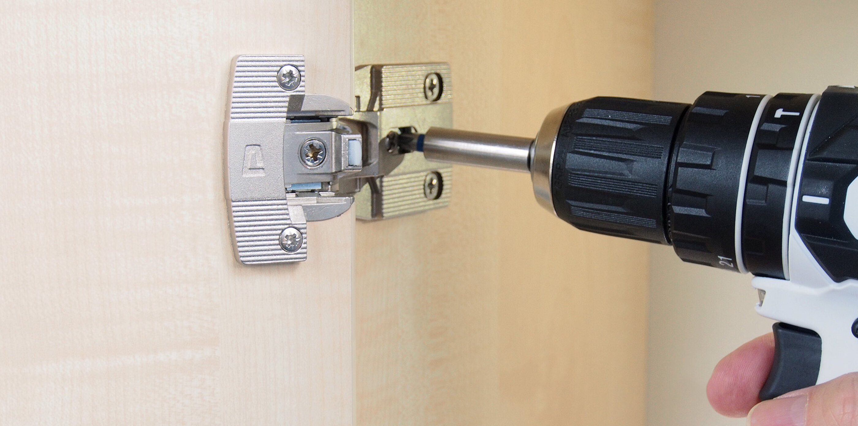 Montage eines PRÄMETA Präzisionsmetall Scharniers an einem Holzschrank. Ein Scharnier von PRÄMETA Präzisionsmetall wird mit einem Akkuschrauber an einem Holzschrank befestigt.