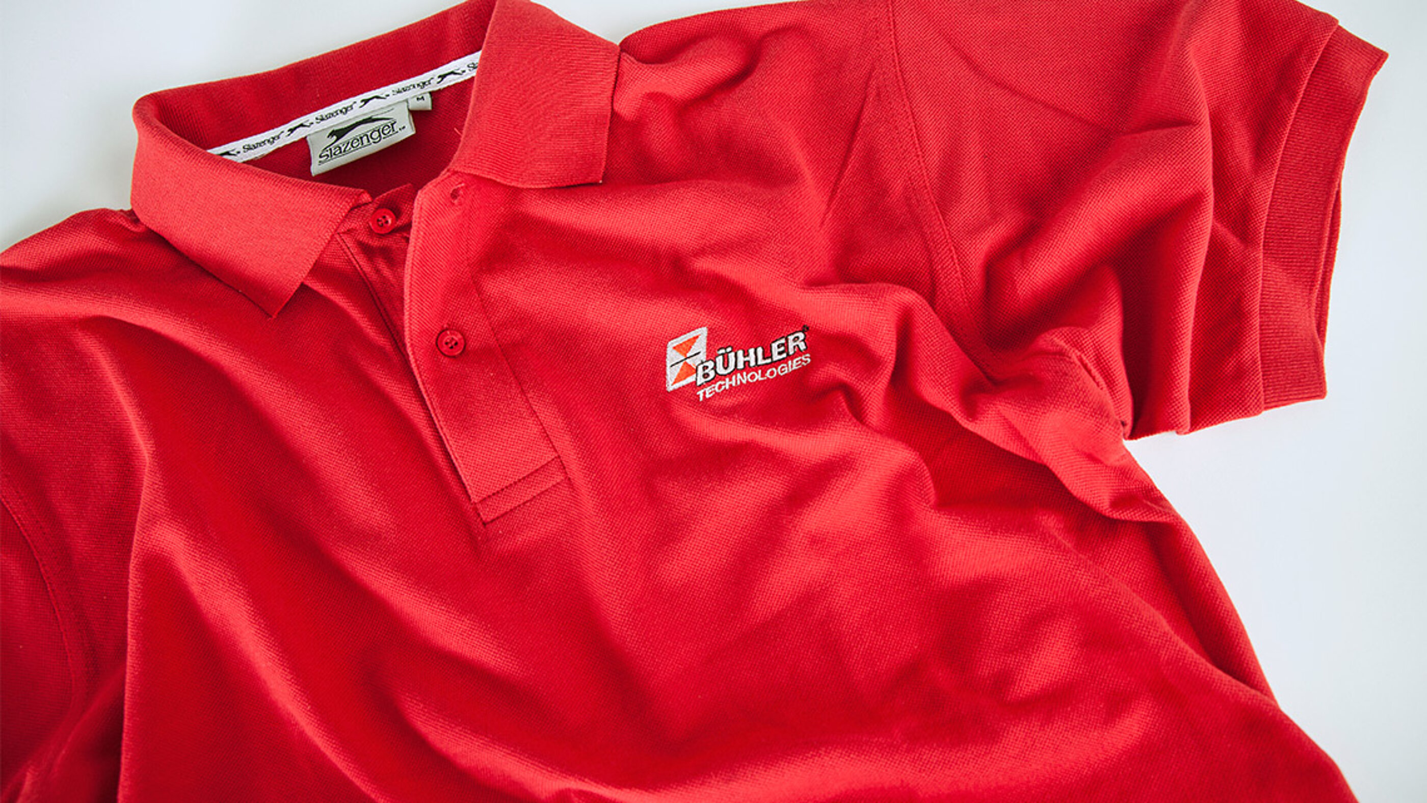 Techniker und Kundenberater tragen Kleidung in Corporate Colour, so dass sie vor Ort und in der Marken-Bildwelt schnell zu erkennen sind. Mitarbeiter Kleidung in der Corporate Colour von BÜHLER Technologies.