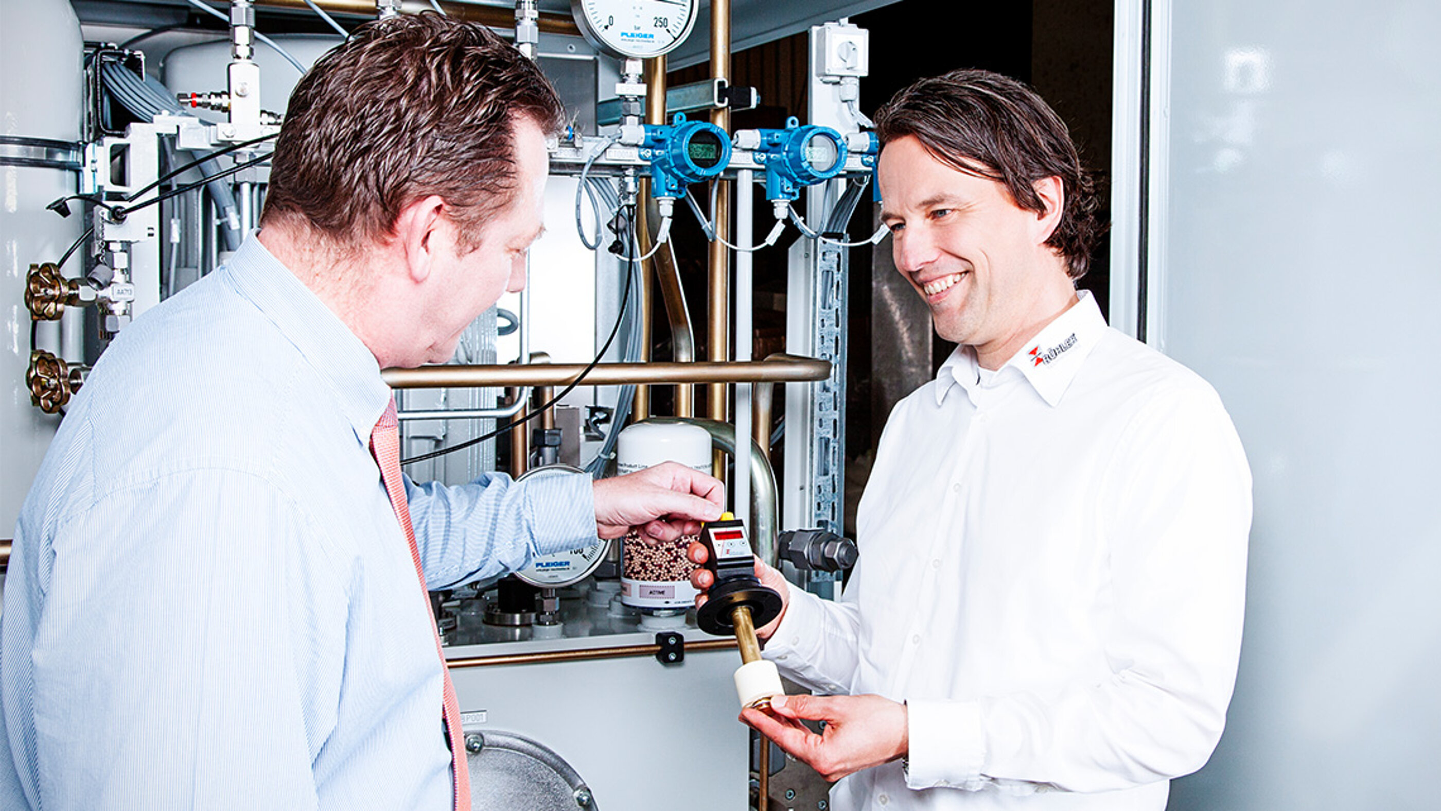 Die Marken-Bildwelt vermittelt Kundennähe und Expertise in verschiedenen Industrien. Die BÜHLER Technologies Bildwelt zeigt eine Kunden Beratung mit Produkt vor einer Anlage.